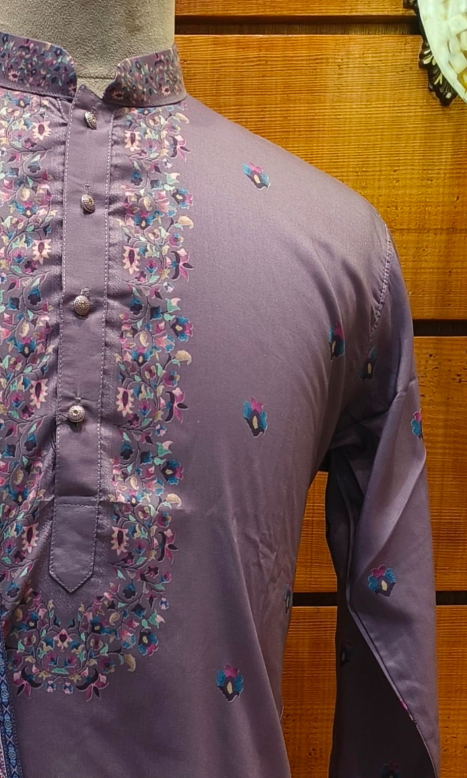 Purple embroidered shirt on a mannequin against a wooden background
