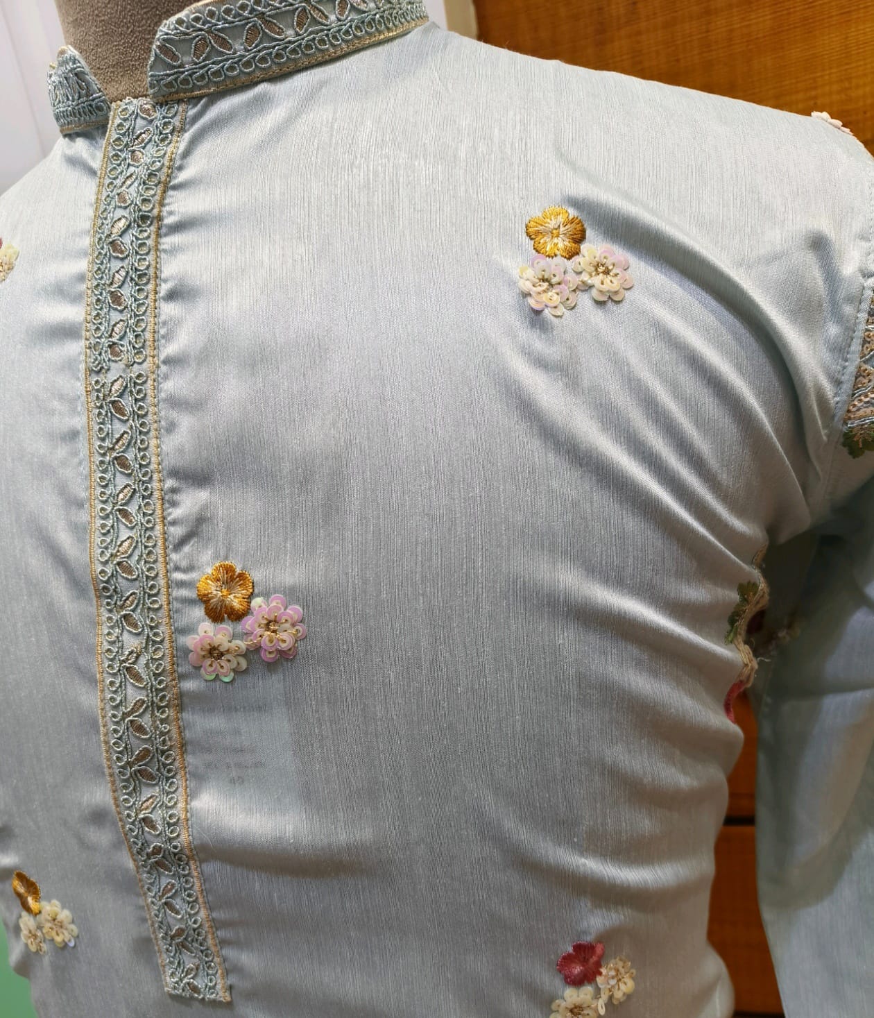 White blouse with floral embroidery and intricate detailing on a mannequin.