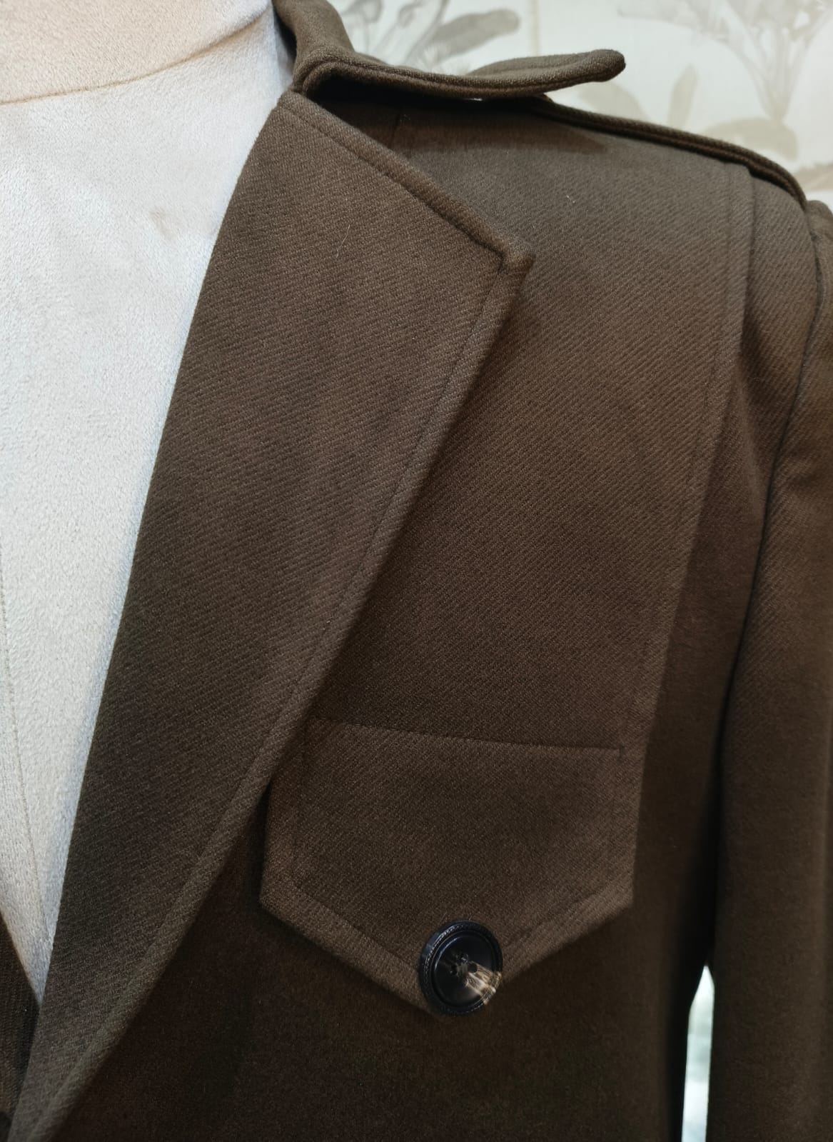Brown coat with a button on a mannequin against a neutral background