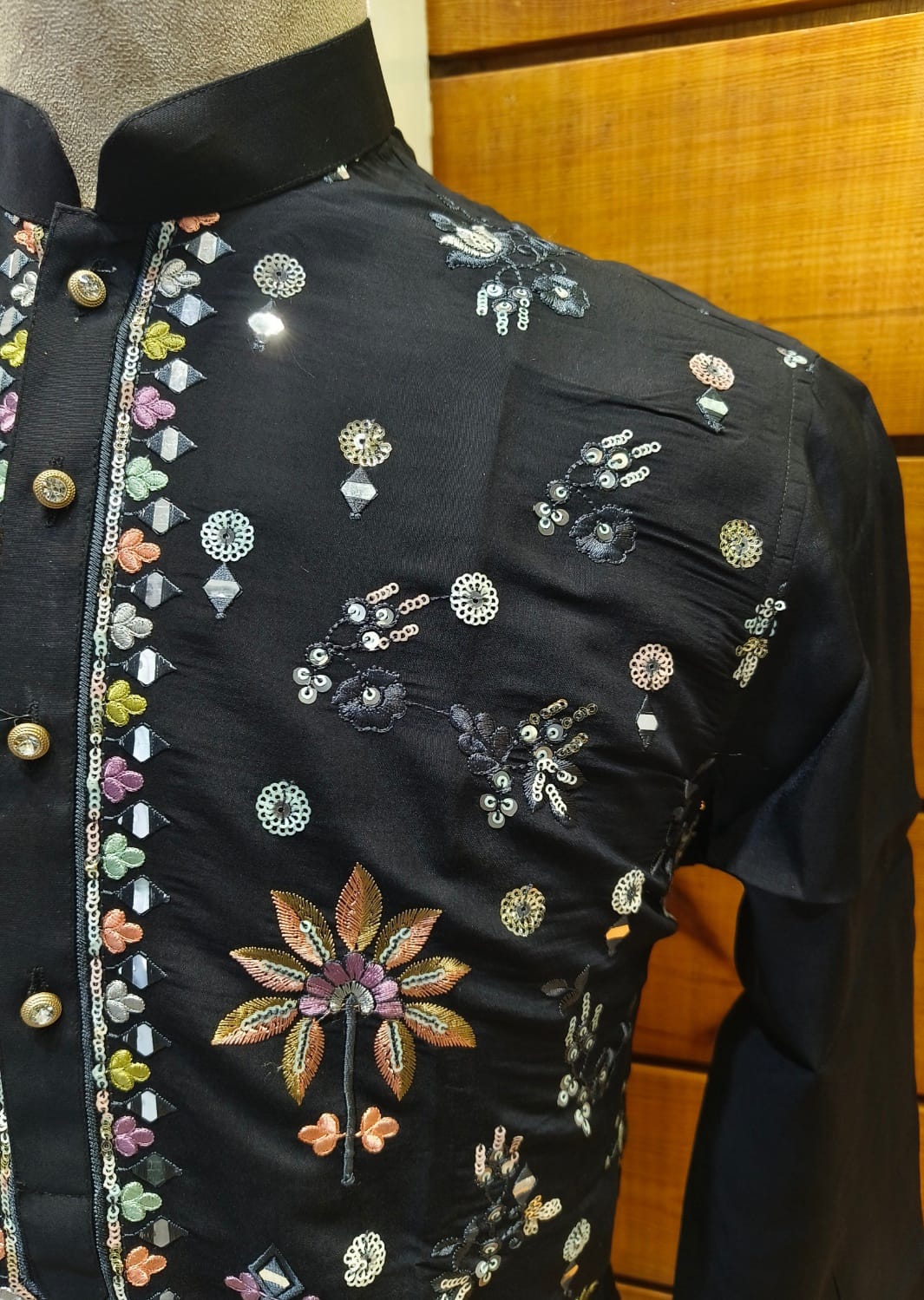 Black embroidered jacket with colorful floral patterns on a wooden surface