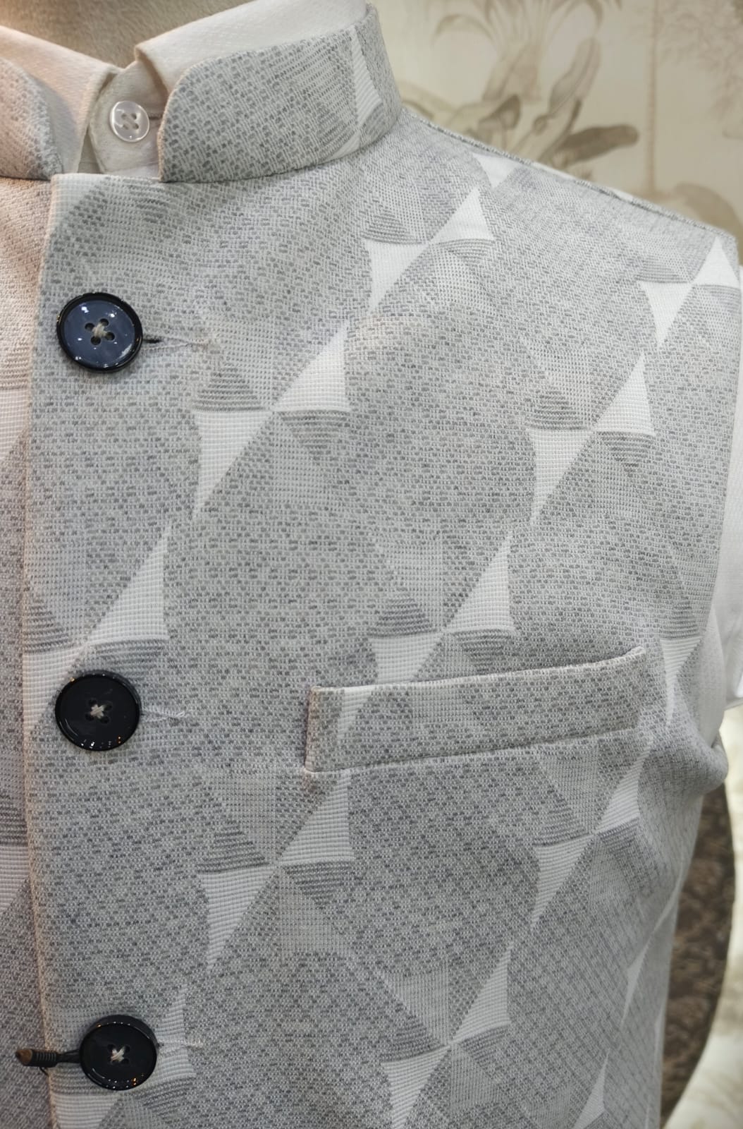 Close-up of a gray patterned shirt with black buttons on a neutral background