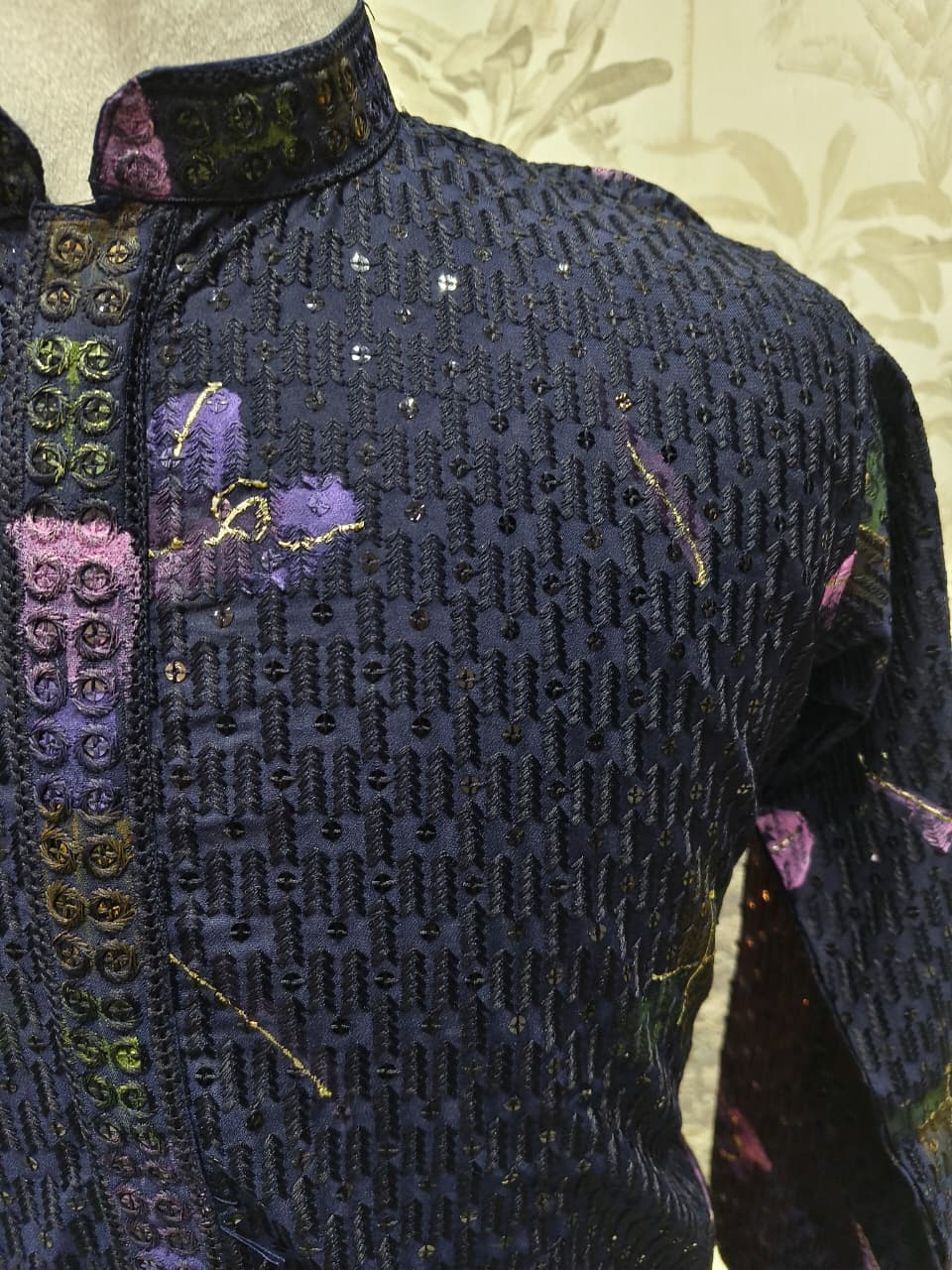 Close-up of a dark blue embroidered garment with floral patterns on a light background