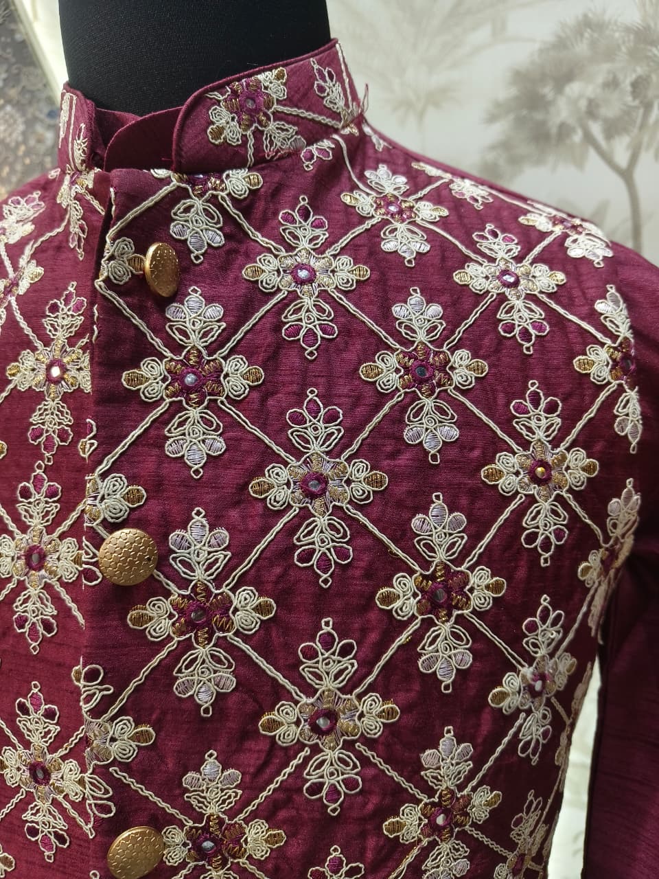Maroon embroidered garment on a mannequin with a white background