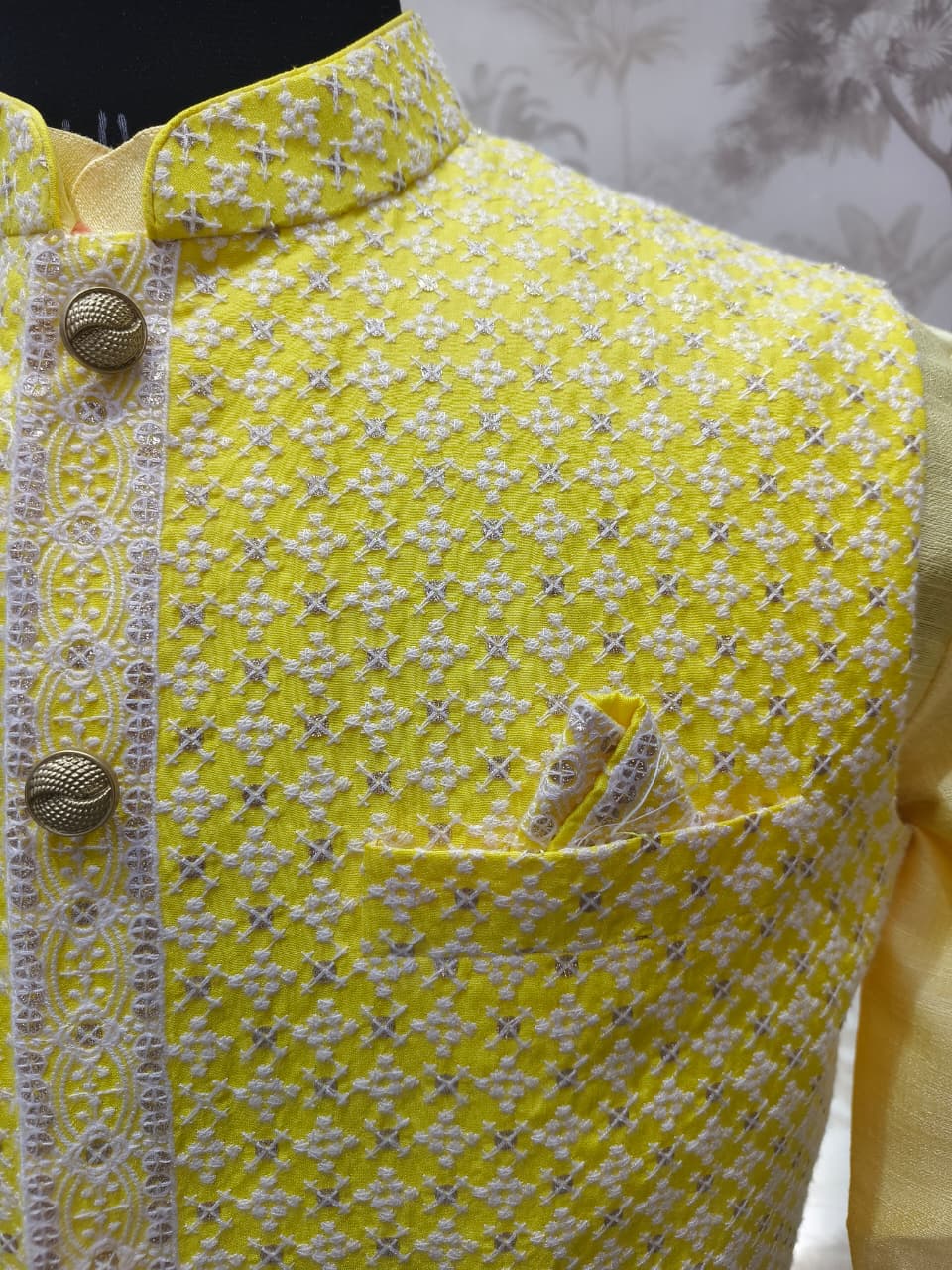 Yellow garment with white floral pattern and decorative buttons on a blurred background