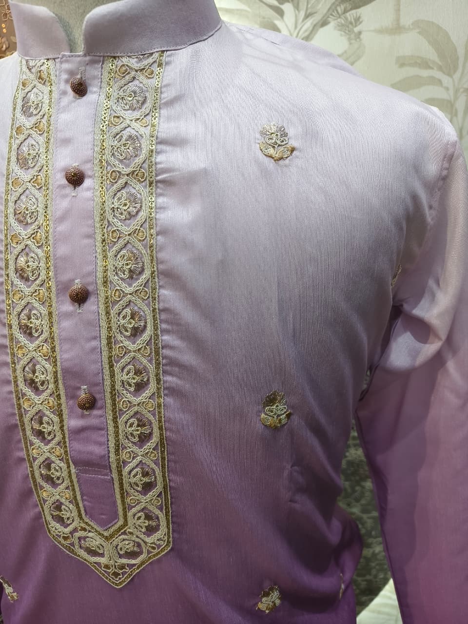Purple shirt with gold embroidery on a mannequin against a floral background