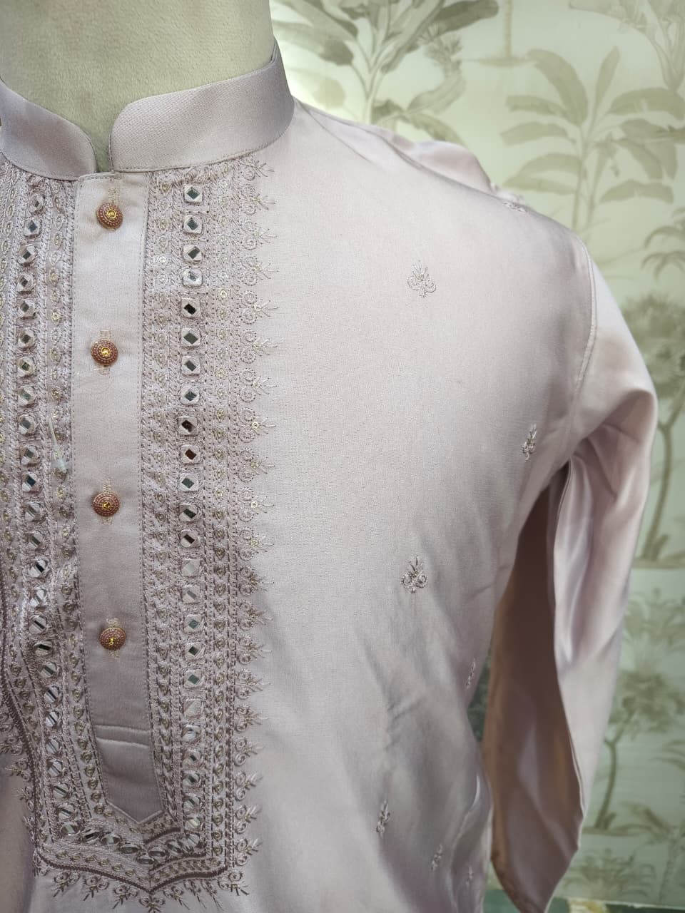 PINK kurta with intricate embroidery on a mannequin against a floral wallpaper background