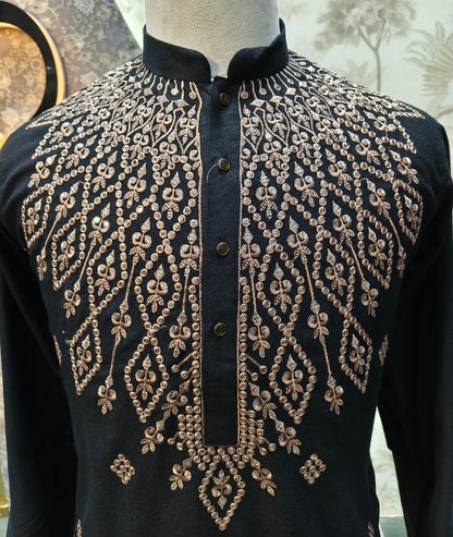 Black shirt with gold embroidery on a mannequin against a neutral background