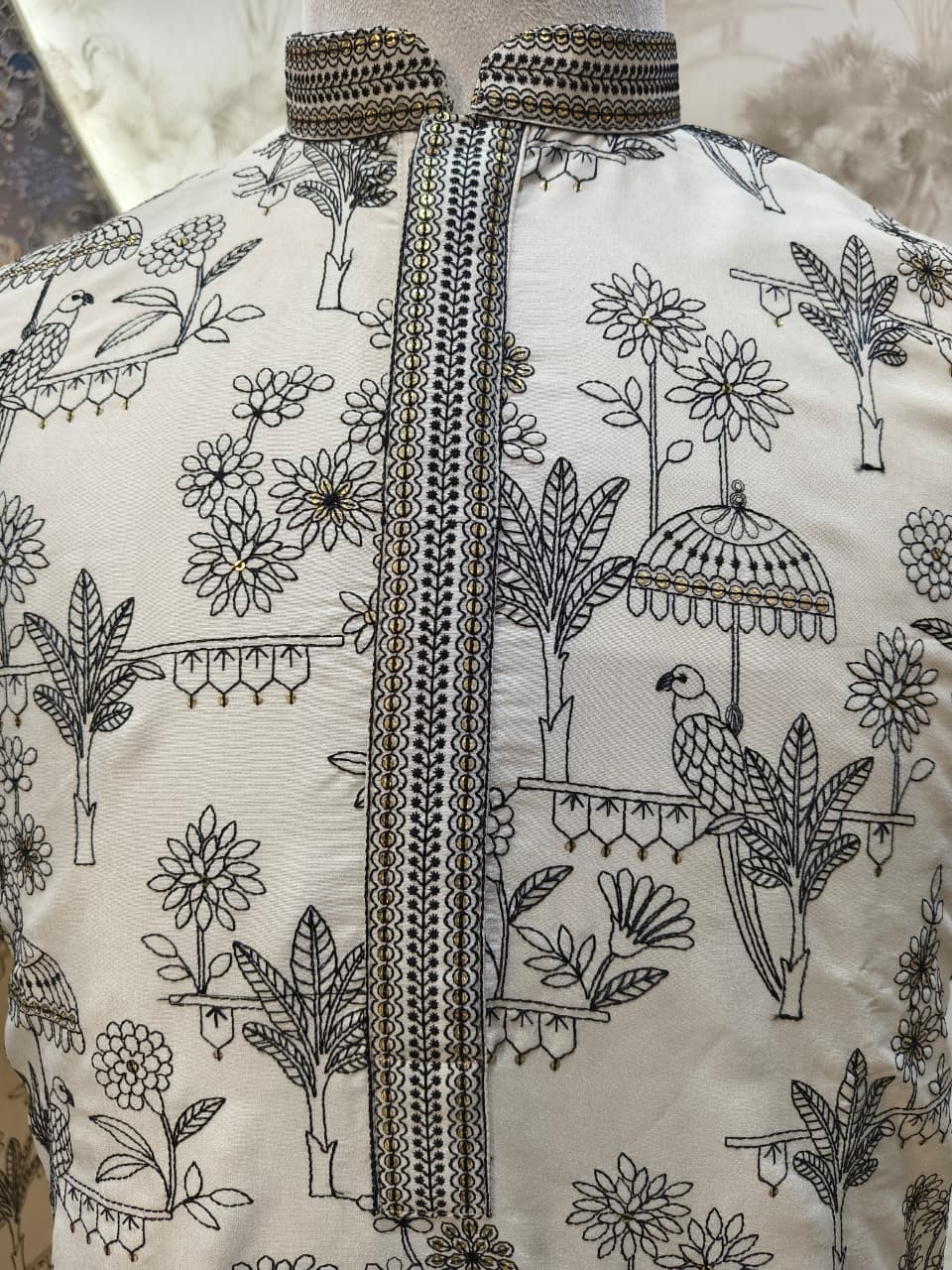 Embroidered garment with floral and bird patterns on a neutral background