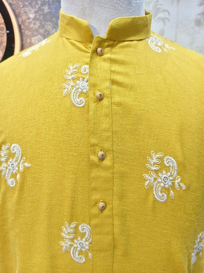 Yellow shirt with white embroidery on a mannequin against a neutral background