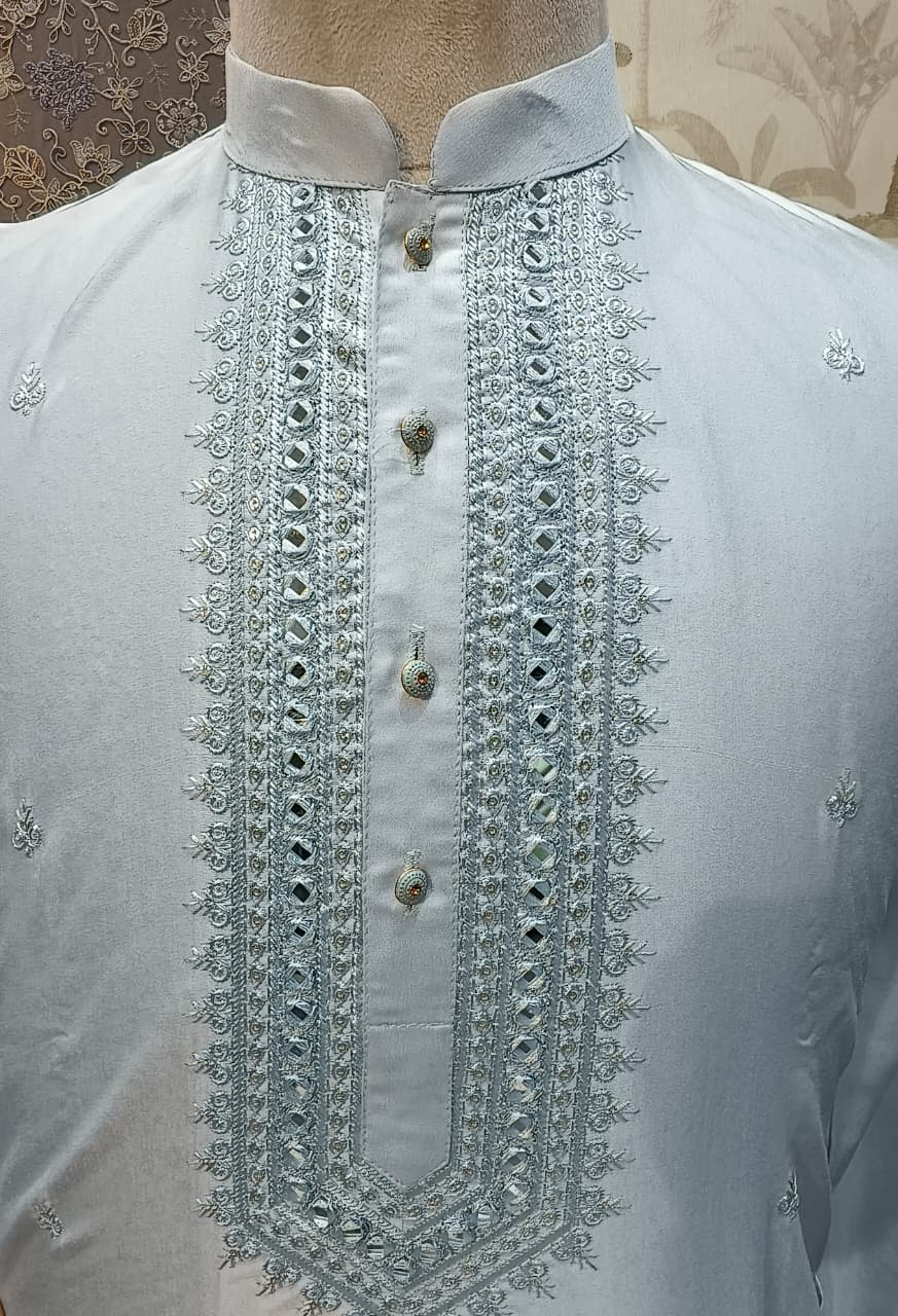 Light blue shirt with intricate silver embroidery on a mannequin against a neutral background