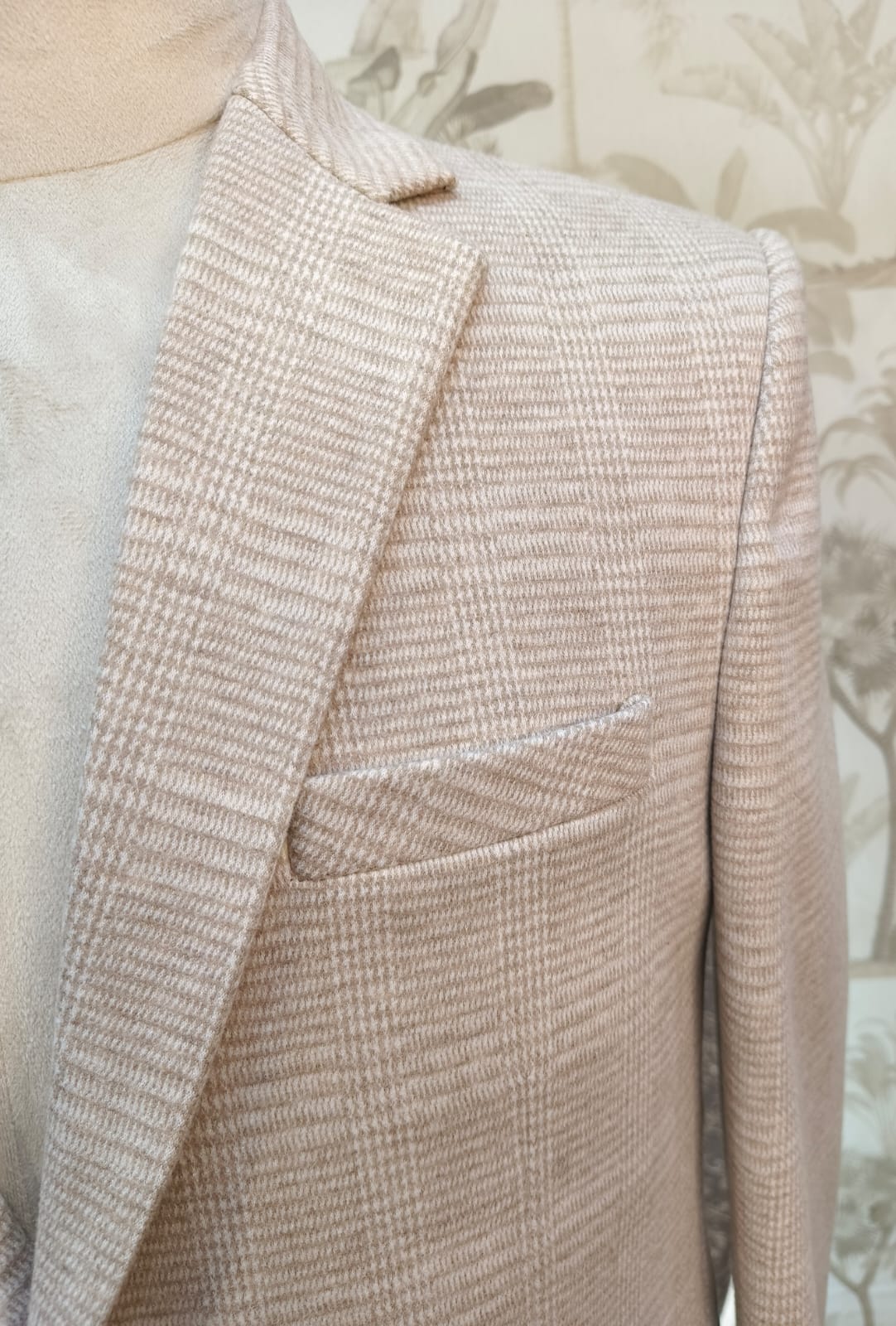 Close-up of a textured beige blazer on a neutral background
