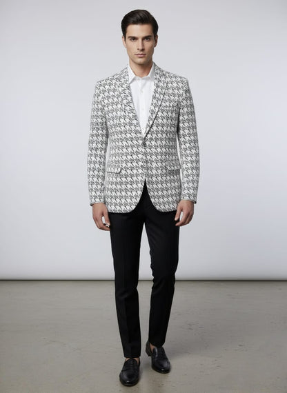 Man wearing a patterned blazer over a white shirt with black pants on a plain background