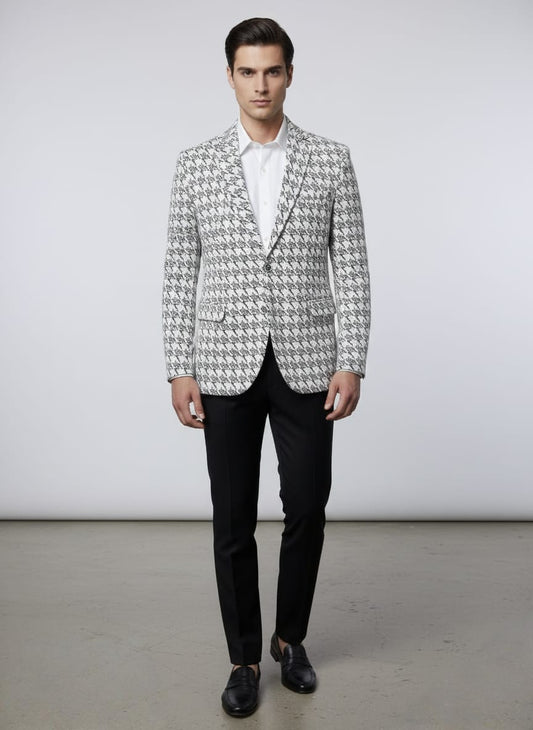 Man wearing a patterned blazer over a white shirt with black pants on a plain background