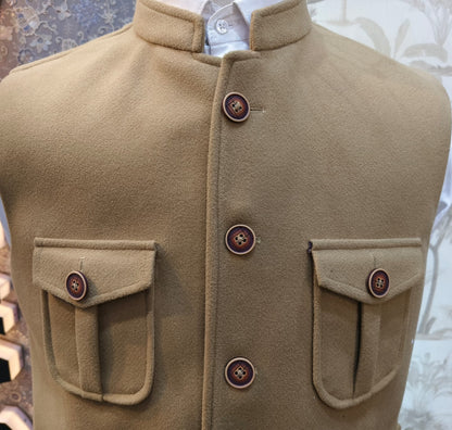 Close-up of a beige coat with button details on a mannequin against a textured background.