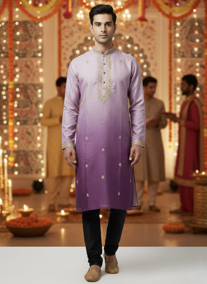 Man wearing a light purple embroidered kurta with black pants in a decorated indoor setting.