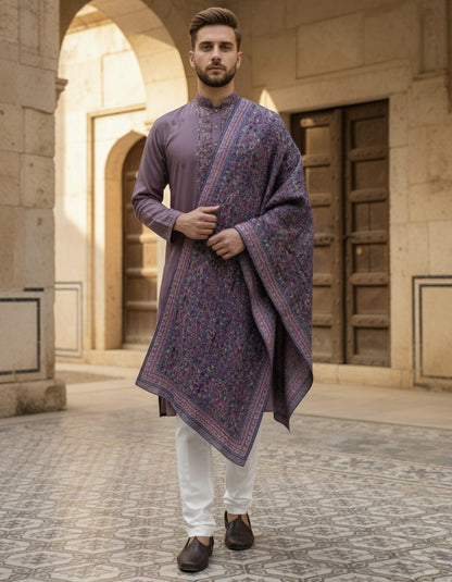 Man wearing a traditional outfit with a patterned shawl in an architectural setting